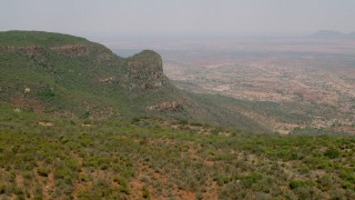 HD stock footage aerial video of flying over green mountains toward a village in Zimbabwe Aerial Stock Footage | CAP_026_097