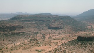 CAP_026_101 - HD stock footage aerial video of passing a village beside green mountains in Zimbabwe