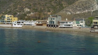 4K aerial stock footage of flying low over ocean, approaching a beachfront home, Malibu, California Aerial Stock Footage | DCA05_102