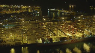 4K aerial stock footage of flying by cargo ship, cranes, containers, Port of Long Beach, California, night Aerial Stock Footage | DCA07_135