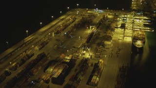 DCA07_144 - 4K aerial stock footage pan across cargo containers, reveal cargo ship, cranes, Port of Long Beach, California, night