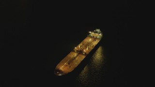 DCA07_149 - 4K aerial stock footage of flying by oil tanker sailing near Port of Long Beach, tilt to black, California, night