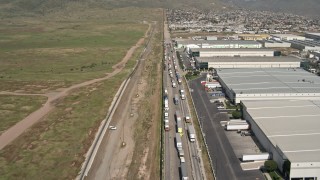 4K aerial stock footage fly over warehouses and trucks by border fence, US/Mexico Border, Tijuana Aerial Stock Footage | DCA08_072E