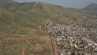 4K aerial stock footage video follow the border fence toward a mountain, US/Mexico Border, Tijuana Aerial Stock Footage | DCA08_074E