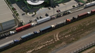 4K aerial stock footage of a ling of big rigs by a warehouse, Tijuana, Mexico Aerial Stock Footage | DCA08_080