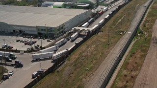 DCA08_081E - 4K aerial stock footage of warehouses and and big rig trucks on the US/Mexico Border, Tijuana