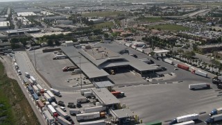 DCA08_089 - 4K aerial stock footage orbit trucks at the border crossing, US/Mexico Border, Otay Mesa, California