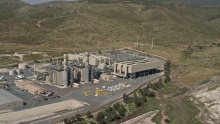 DCA08_095E - 4K aerial stock footage pan across a green field to reveal and orbit a power plant in Otay Mesa, California