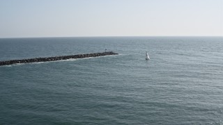 4K aerial stock footage fly over breakwaters and track a sailboat, Mission Beach, California Aerial Stock Footage | DCA08_154E