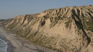 DCA08_251E - 4K aerial stock footage flyby coastal cliffs and beach, ascend to reveal hang gliders, La Jolla, California