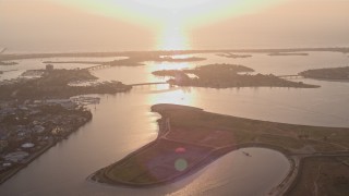 DCA08_288 - 4K aerial stock footage of flying by an island in a bay, reveal SeaWorld San Diego theme park, California, Sunset