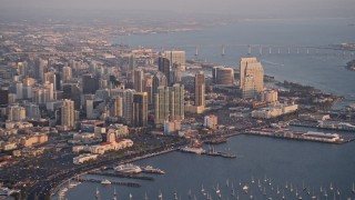 4K aerial stock footage of a high altitude approach to skyscrapers, pan across Downtown San Diego, California, Sunset Aerial Stock Footage | DCA08_291