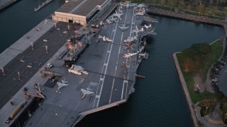 DCA08_304E - 4K aerial stock footage reveal and orbit aircraft carrier, USS Midway in Downtown San Diego, California at sunset