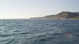 5K aerial stock footage fly low over the ocean to approach coast of Malibu and tilt to waves, California Aerial Stock Footage | DCLA_159