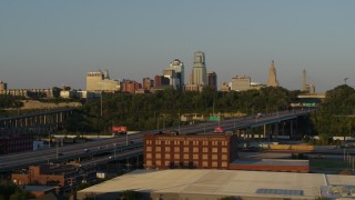 5.7K aerial stock footage of the city's skyline seen while flying by freeway at sunset in Downtown Kansas City, Missouri Aerial Stock Footage | DX0001_001162