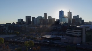 5.7K aerial stock footage flyby the rising sun behind the city skyline, reveal the arena in Downtown Denver, Colorado Aerial Stock Footage | DX0001_001631