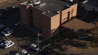 5.7K aerial stock footage of a reverse view of a brick police station and flag in Denver, Colorado Aerial Stock Footage | DX0001_001765