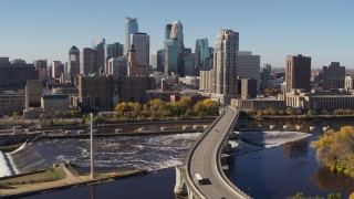 5.7K aerial stock footage flying by a bridge spanning the river with a view of the skyline, Downtown Minneapolis, Minnesota Aerial Stock Footage | DX0001_002143