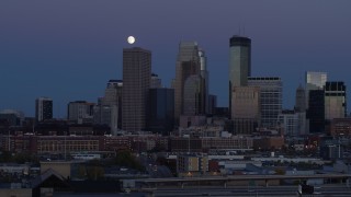 5.7K aerial stock footage of passing by the city's skyline at twilight with moon in the sky, Downtown Minneapolis, Minnesota Aerial Stock Footage | DX0001_002263