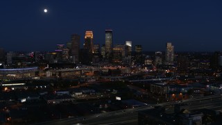 5.7K aerial stock footage of a reverse view of the moon above city's skyline at twilight, Downtown Minneapolis, Minnesota Aerial Stock Footage | DX0001_002288