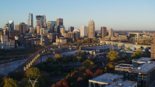 5.7K aerial stock footage flyby bridge and river at sunrise, reveal power plant, with view of skyline, Downtown Minneapolis, Minnesota Aerial Stock Footage | DX0001_002297