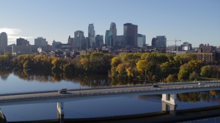 DX0001_002350 - 5.7K aerial stock footage of flying by the bridge over river with a view of the skyline of Downtown Minneapolis, Minnesota