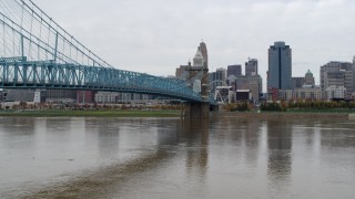 DX0001_002641 - 5.7K aerial stock footage descend by the Roebling Bridge spanning Ohio River with view of the city skyline, Downtown Cincinnati, Ohio