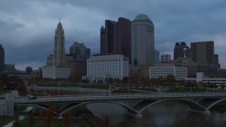 5.7K aerial stock footage ascend over bridge for view of city skyline by the Scioto River at sunset, Downtown Columbus, Ohio Aerial Stock Footage | DX0001_002741