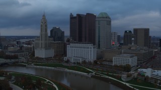 5.7K aerial stock footage fly away from and by city skyline by the Scioto River at sunset, Downtown Columbus, Ohio Aerial Stock Footage | DX0001_002742