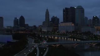 5.7K aerial stock footage flying by the river and the city skyline at twilight to reveal a bridge in Downtown Columbus, Ohio Aerial Stock Footage | DX0001_002769