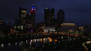 DX0001_002792 - 5.7K aerial stock footage reverse view of a bridge spanning the river and city skyline at twilight during descent, Downtown Columbus, Ohio