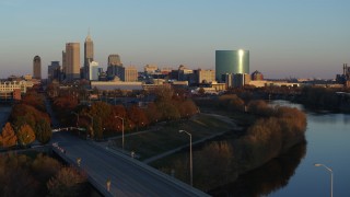 DX0001_002926 - 5.7K aerial stock footage of the city's skyline at sunset seen from White River, reveal bridge, Downtown Indianapolis, Indiana