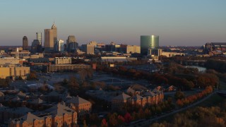 5.7K aerial stock footage of the city's skyline at sunset seen while ascending from White River, Downtown Indianapolis, Indiana Aerial Stock Footage | DX0001_002927