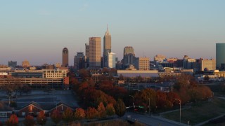 5.7K aerial stock footage of the city's skyline at sunset, seen during ascent from trees, Downtown Indianapolis, Indiana Aerial Stock Footage | DX0001_002931