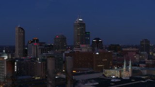 DX0001_002972 - 5.7K aerial stock footage reverse view of giant skyscrapers of the city skyline at twilight, seen from smoke stacks, Downtown Indianapolis, Indiana