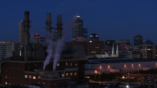 5.7K aerial stock footage descend by factory smoke stacks with view of the city skyline at twilight, Downtown Indianapolis, Indiana Aerial Stock Footage | DX0001_002977