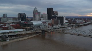 DX0001_003065 - 5.7K aerial stock footage of arena and city skyline seen from bridge spanning river at sunset, Downtown Louisville, Kentucky