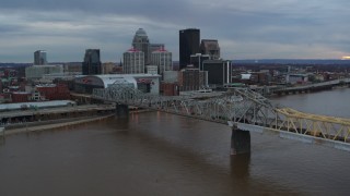 5.7K aerial stock footage of the arena and city skyline seen from a bridge spanning Ohio River at sunset, Downtown Louisville, Kentucky Aerial Stock Footage | DX0001_003066