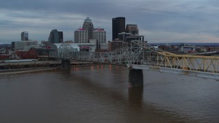 DX0001_003067 - 5.7K aerial stock footage descend by bridge with view of the skyline at sunset, Downtown Louisville, Kentucky