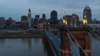 5.7K aerial stock footage flyby the Roebling Bridge over the river at sunset, approach the skyline, Downtown Cincinnati, Ohio Aerial Stock Footage | DX0001_003154