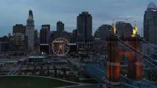 5.7K aerial stock footage of Ferris wheel and city skyline at sunset during descent by bridge, Downtown Cincinnati, Ohio Aerial Stock Footage | DX0001_003156