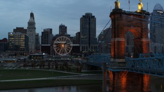 DX0001_003157 - 5.7K aerial stock footage pass Roebling Bridge to approach Ferris wheel and city skyline at sunset, Downtown Cincinnati, Ohio