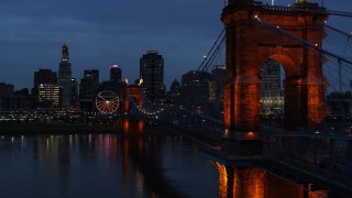 5.7K aerial stock footage stationary view of city skyline behind Roebling Bridge lit up at twilight, seen from Ohio River, Downtown Cincinnati, Ohio Aerial Stock Footage | DX0001_003172