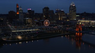 5.7K aerial stock footage flying by lights of city skyline and bridge at twilight, seen from across river, Downtown Cincinnati, Ohio Aerial Stock Footage | DX0001_003179