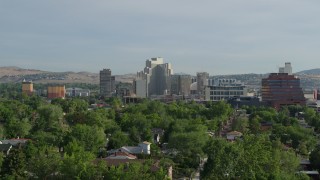 DX0001_006_016 - 5.7K aerial stock footage of a view of casino resorts seen while descending behind neighborhood trees in Reno, Nevada