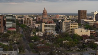 5.7K aerial stock footage of passing by the Texas State Capitol and office buildings at sunset in Downtown Austin, Texas Aerial Stock Footage | DX0002_104_035