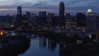 5.7K aerial stock footage reveal Lady Bird Lake and Congress Avenue Bridge, focus on skyline at twilight in Downtown Austin, Texas Aerial Stock Footage | DX0002_110_048