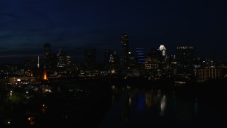 DX0002_111_016 - 5.7K aerial stock footage approach waterfront skyline on the opposite shore of Lady Bird Lake during ascent at night in Downtown Austin, Texas