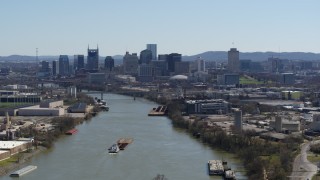 5.7K aerial stock footage flying by barge sailing the river toward the city's skyline, Downtown Nashville, Tennessee Aerial Stock Footage | DX0002_112_022