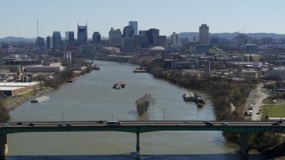 DX0002_112_027 - 5.7K aerial stock footage flyby bridge with view of barge sailing toward city's skyline, Downtown Nashville, Tennessee